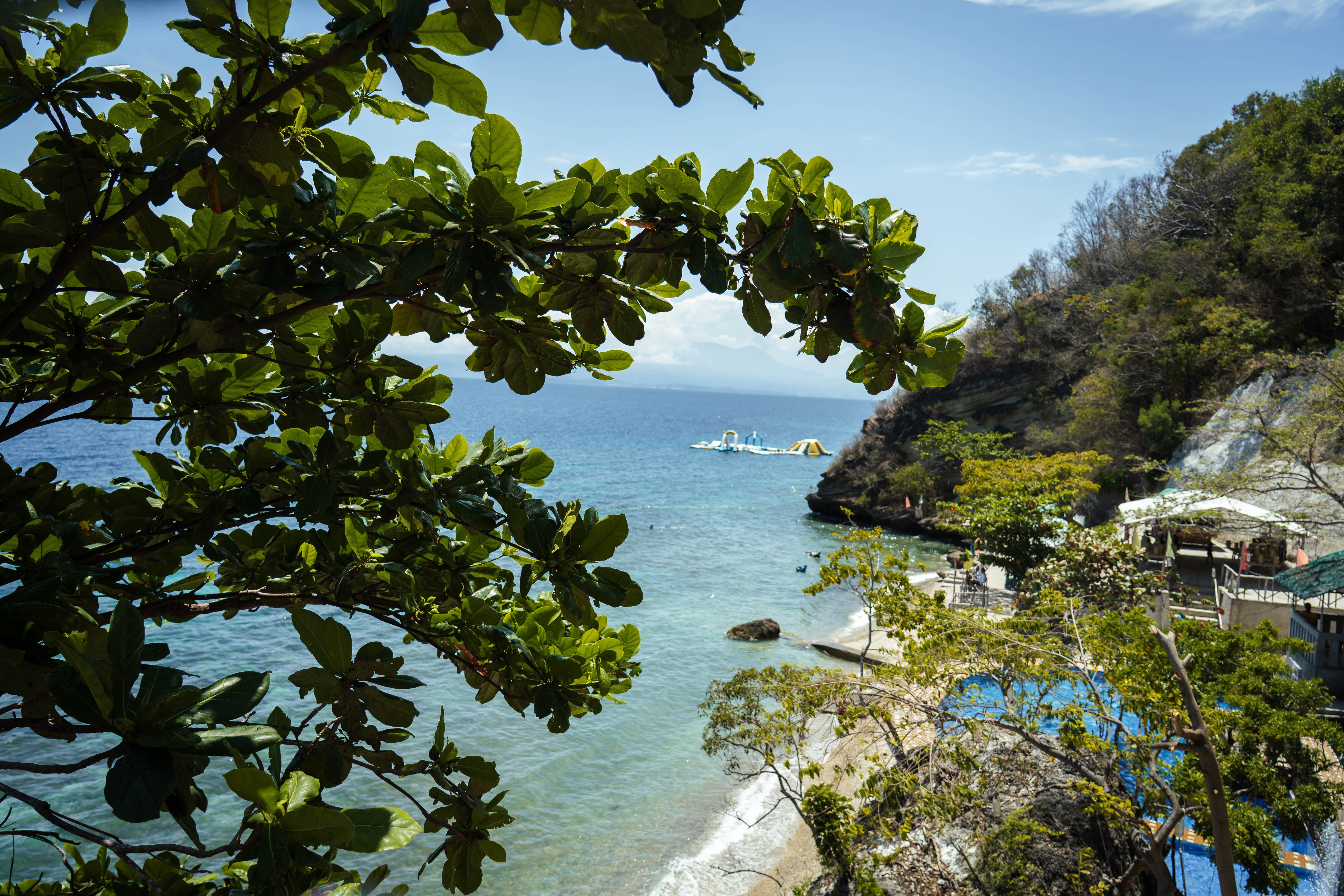 Scenic cove and turquoise waters framed by tropical trees at Brizamar Beach Resort Batangas