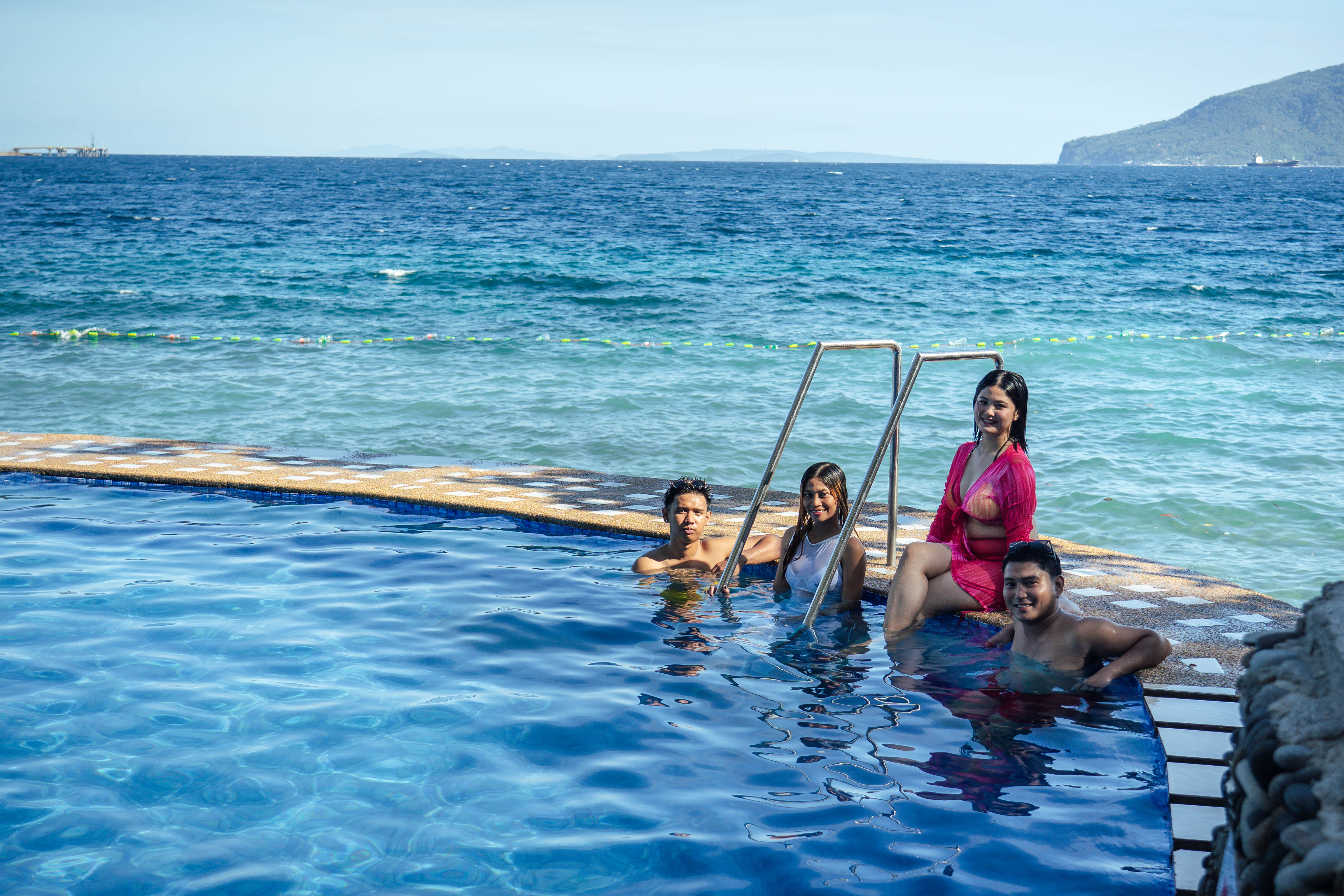 Friends swimming in the beachfront infinity pool with ocean views at Brizamar Beach Resort Batangas City