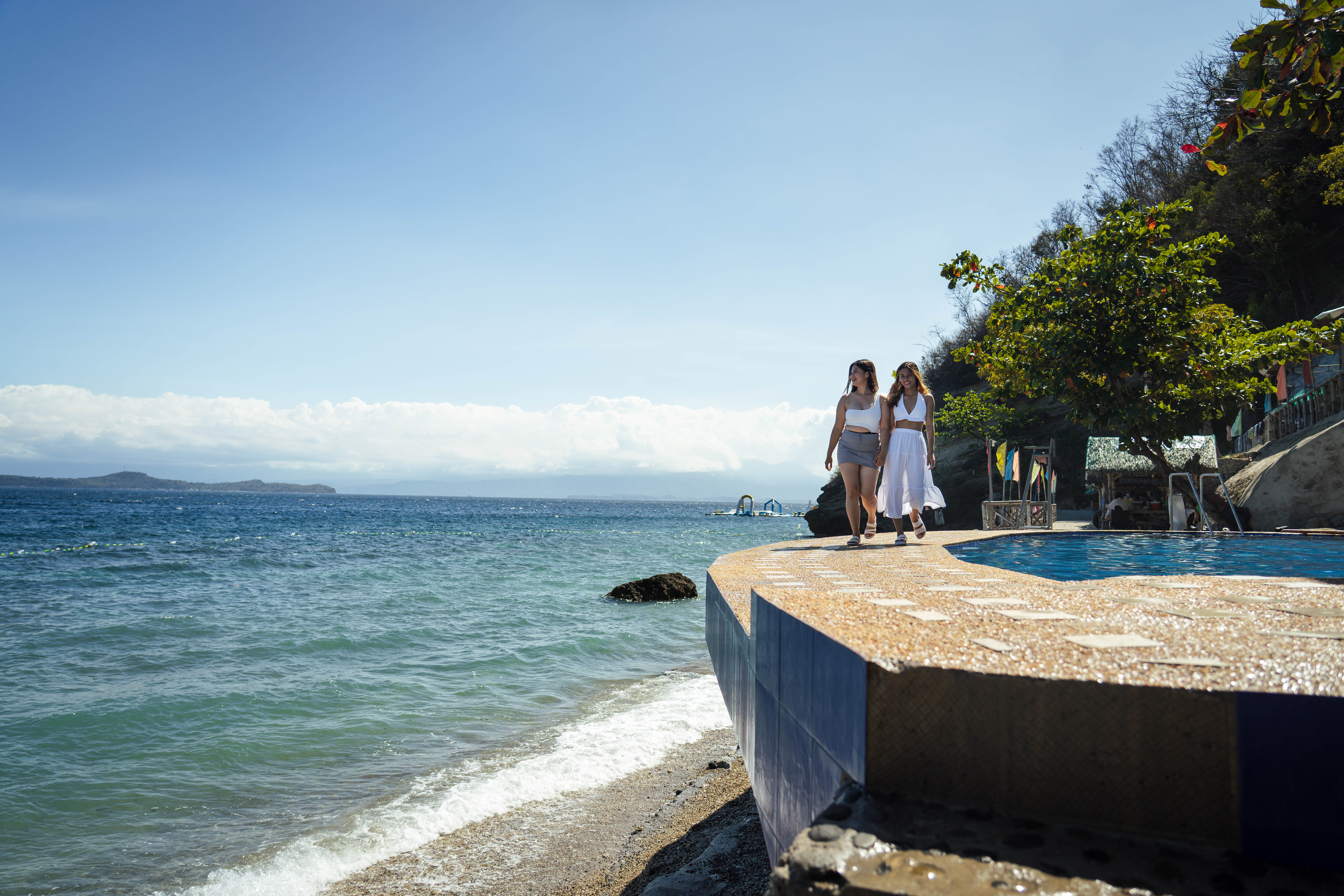 Guests walking along the poolside with panoramic ocean views at Brizamar Beach Resort Batangas City